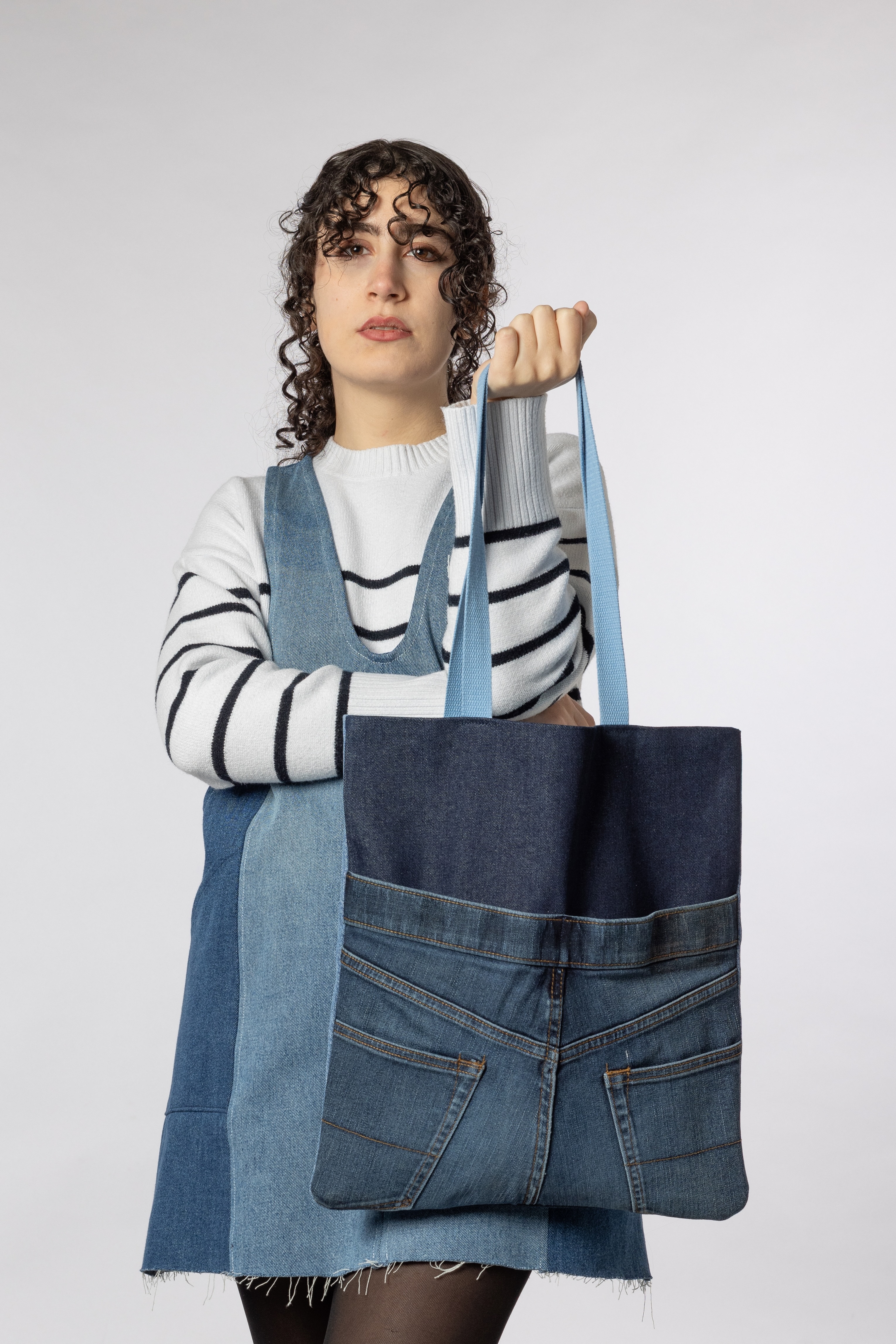 A female model holding an Atlas tote back with its back visible.
